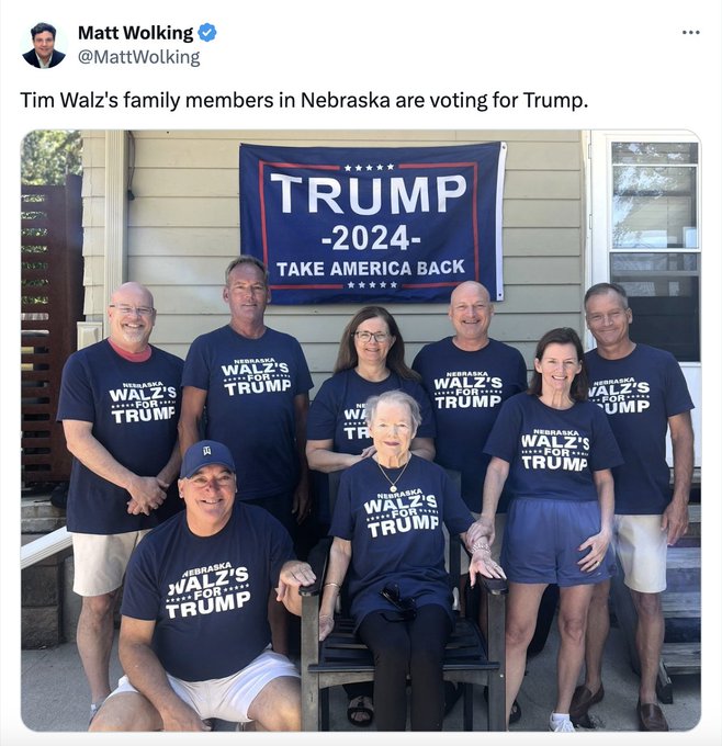 The photo shows eight smiling people wearing navy pro Trump shirts